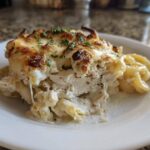 A generous serving of Cheesy Chicken Alfredo Bake with Mozzarella showing layers of chicken, pasta, and a golden, bubbly cheese topping.