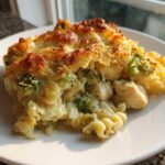 A serving of Cheesy Chicken and Broccoli Pasta Bake with a golden, bubbly cheese crust on a white plate.