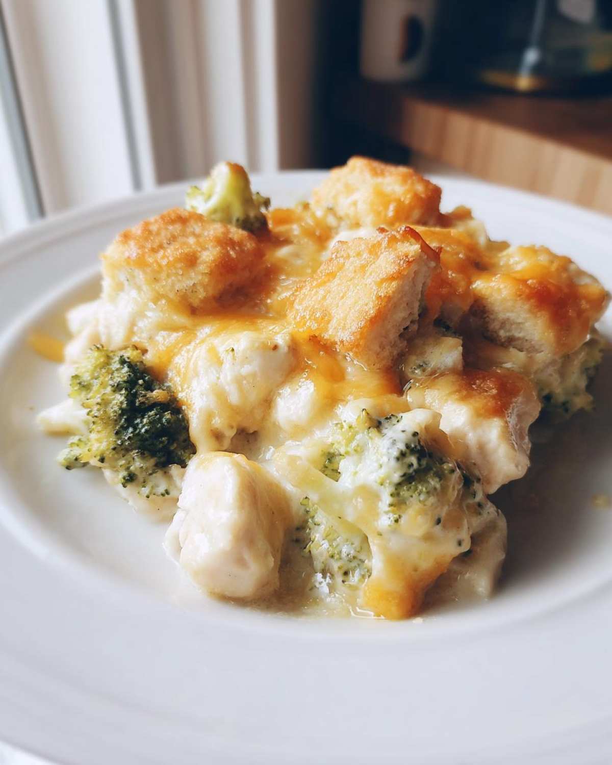 A close-up serving of Cheesy Chicken and Broccoli Bake Comfort Dish topped with melted cheddar and croutons.