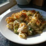 A serving of Cheesy Chicken and Broccoli Pasta Bake with a golden, crispy breadcrumb topping on a white plate.