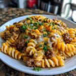 A close-up of Cheesy Ground Beef Pasta Skillet featuring rotini pasta, ground beef, and melted cheddar and mozzarella cheese, topped with parsley.