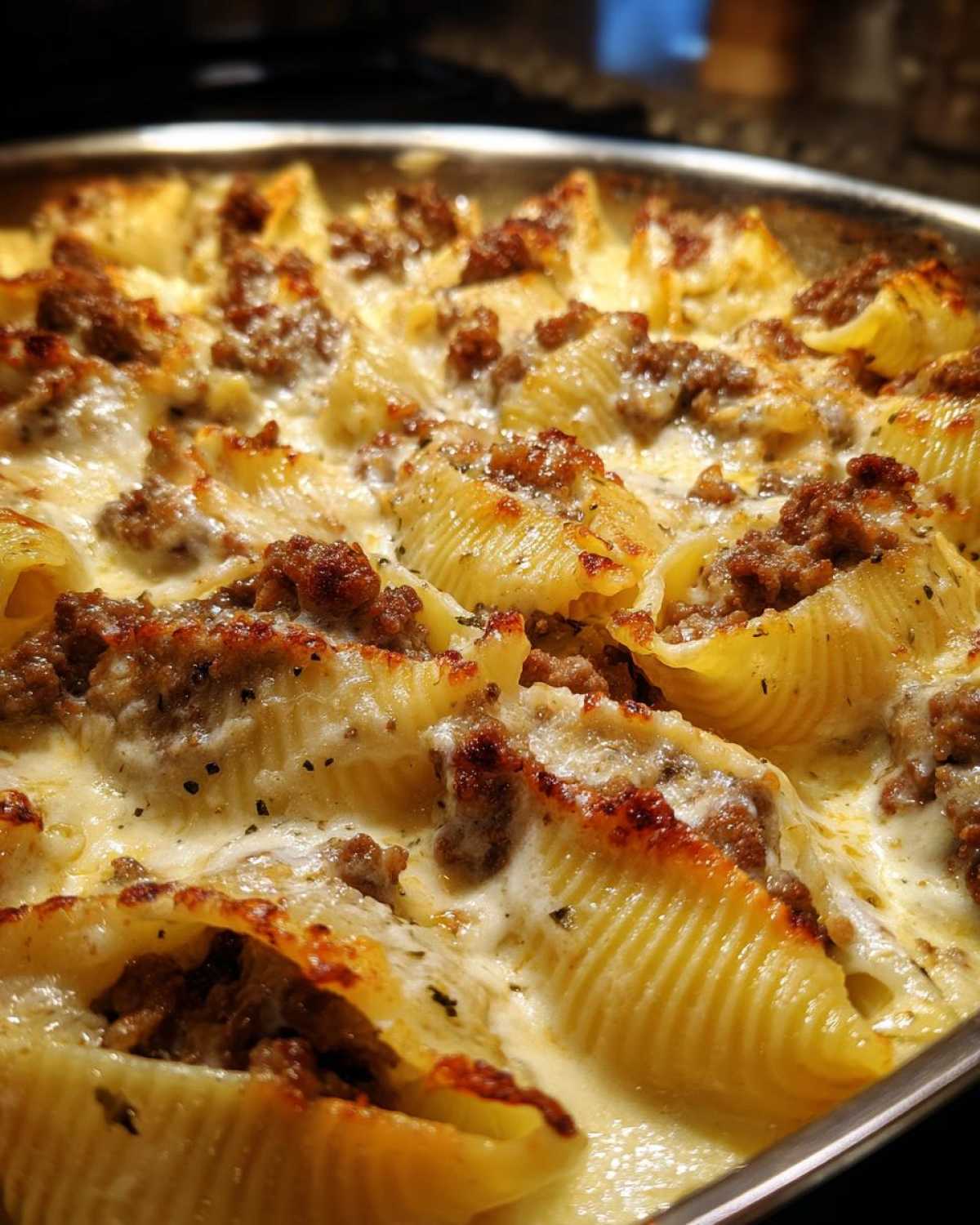 Close-up of baked Cheesy Ground Beef Stuffed Shells with a rich cream sauce and browned cheese topping.