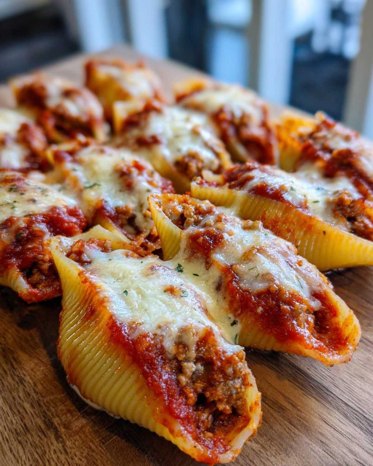 Close-up of baked Cheesy Ground Beef Stuffed Shells topped with melted mozzarella and sauce.