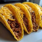 Four crispy tacos filled with seasoned ground beef, creamy filling, and shredded cheese, showcasing the Cheesy Ground Beef Tacos recipe.