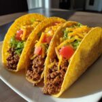 Three crispy hard-shell Cheesy Ground Beef Tacos filled with seasoned meat, lettuce, tomatoes, and shredded cheese.