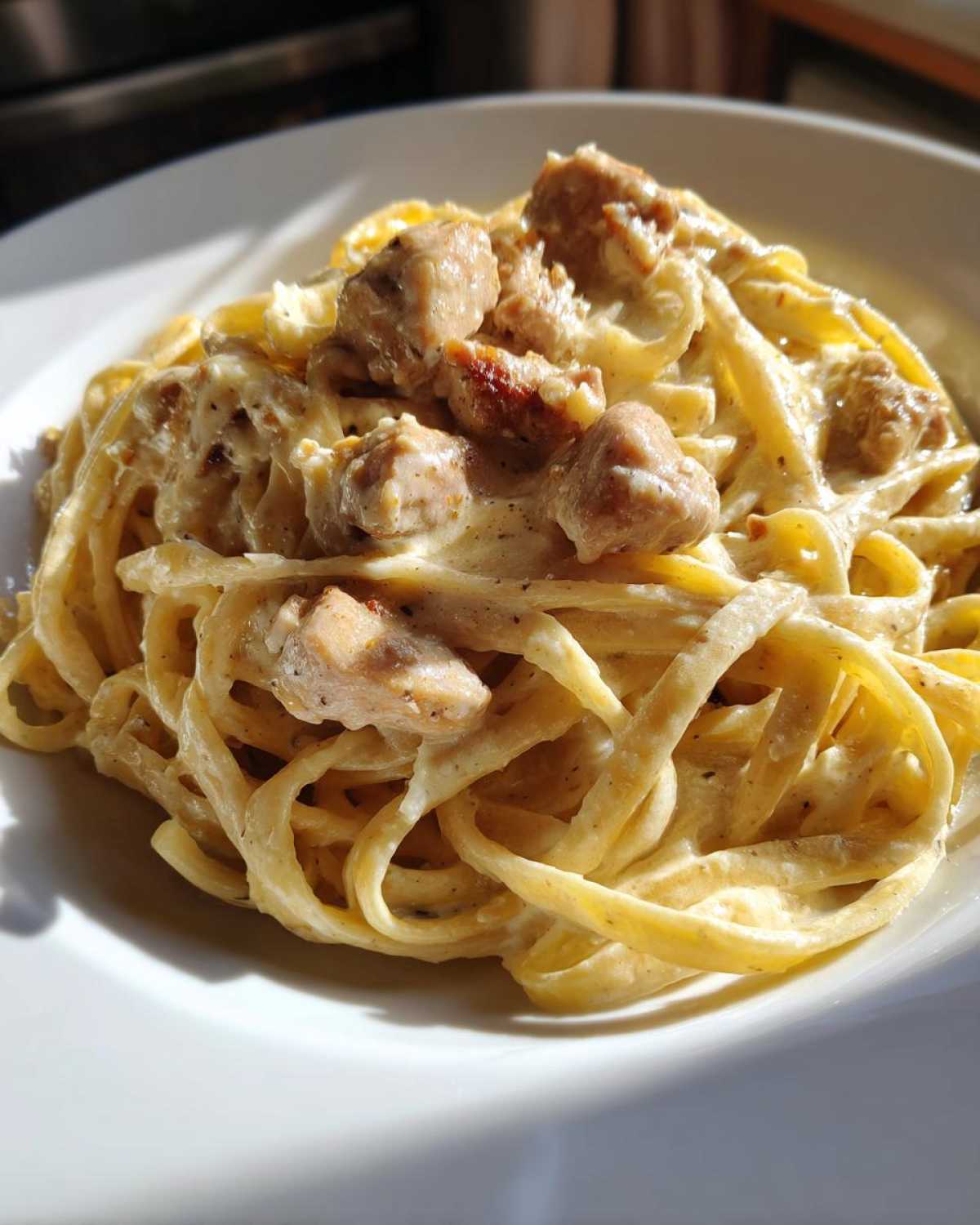 Close-up of fettuccine pasta coated in rich Alfredo sauce with chunks of seasoned chicken, part of the Creamy Alfredo Chicken Pasta Easy Recipe.