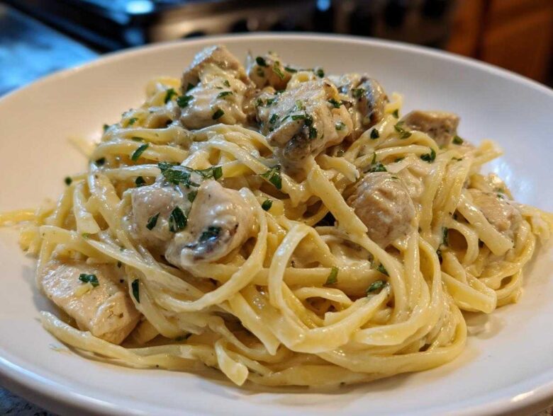 Close-up of fettuccine pasta coated in rich sauce with chunks of chicken, part of the Creamy Alfredo Chicken Pasta Easy Recipe.