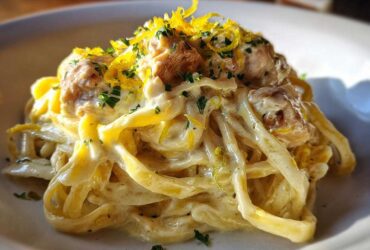 A close-up of Creamy Lemon Garlic Pasta with Chicken, tossed in a rich sauce and topped with lemon zest and parsley.