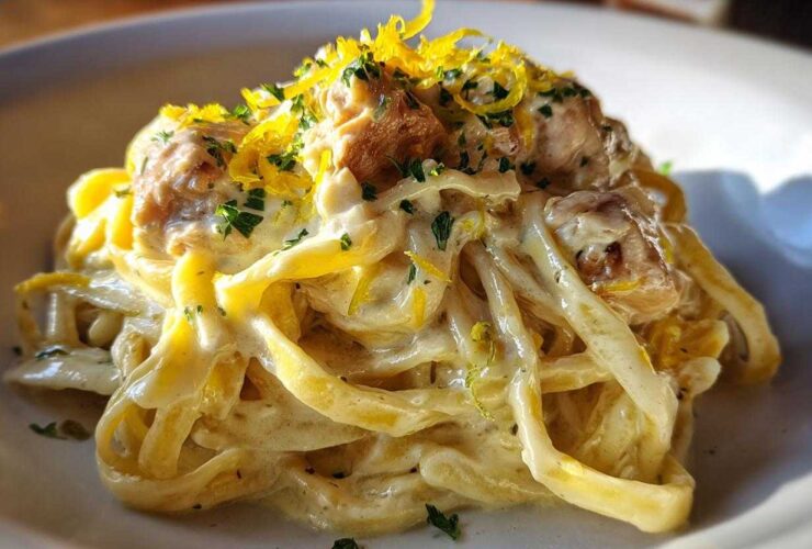A close-up of Creamy Lemon Garlic Pasta with Chicken, tossed in a rich sauce and topped with lemon zest and parsley.