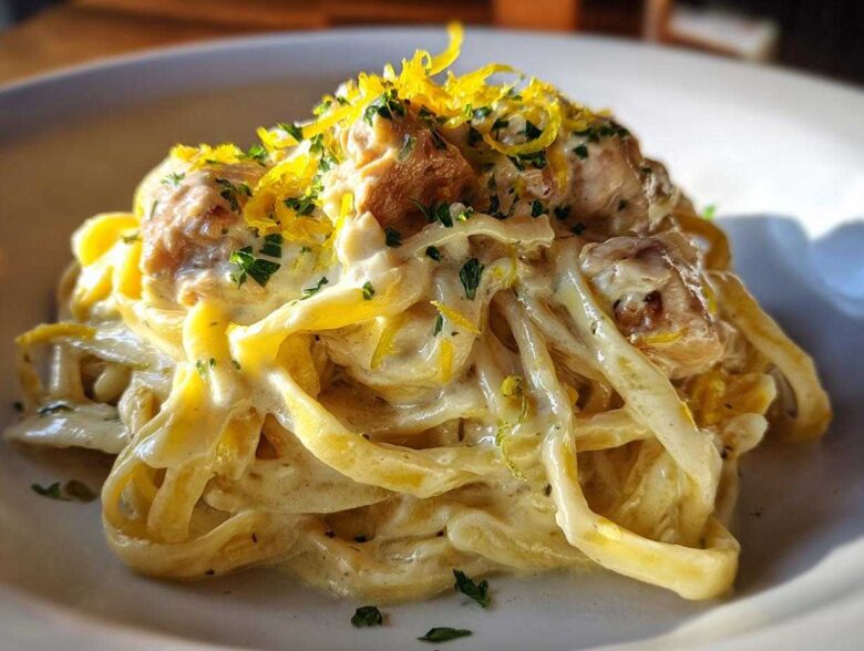 A close-up of Creamy Lemon Garlic Pasta with Chicken, tossed in a rich sauce and topped with lemon zest and parsley.
