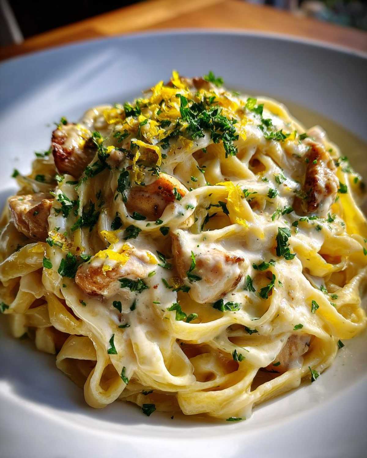 Close-up of creamy lemon garlic pasta with chicken, topped with fresh parsley and lemon zest.