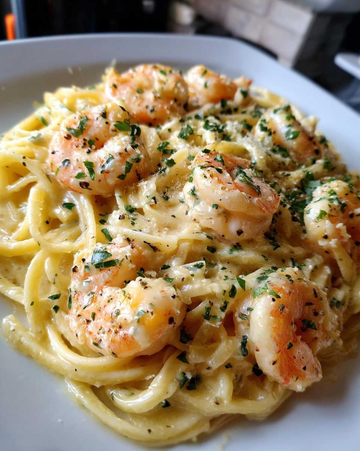Close-up of Creamy Lemon Garlic Shrimp Pasta topped with fresh parsley and grated cheese.