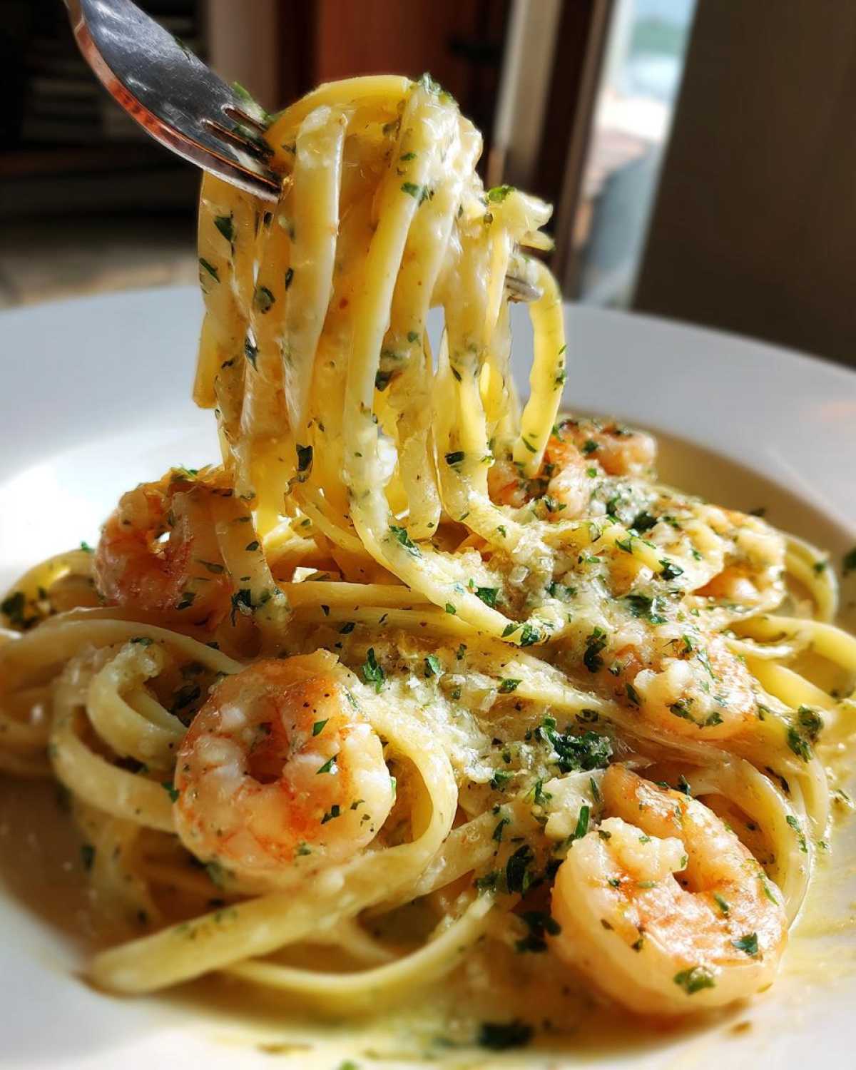 A fork twirls linguine noodles coated in a creamy sauce with shrimp, showcasing the Fresh Taste of Creamy Lemon Garlic Shrimp Pasta.