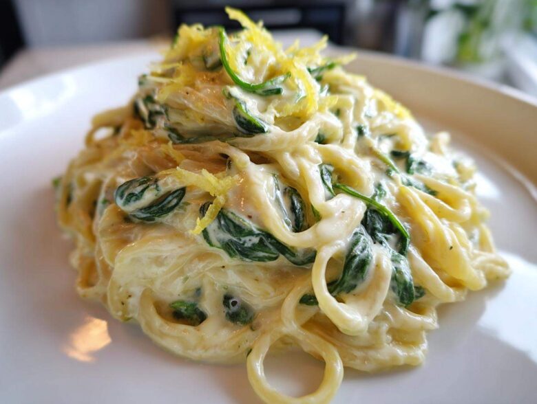 A close-up of a serving of Creamy Lemon Ricotta Pasta with Spinach, topped with lemon zest.