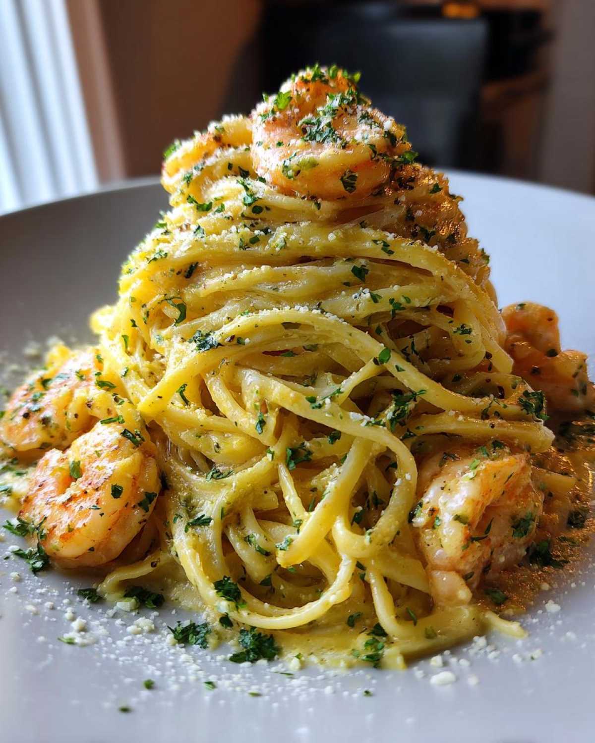 A tall mound of creamy lemon shrimp pasta, topped with cooked shrimp and fresh parsley.