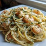 Close-up of a serving of Creamy Lemon Shrimp Pasta with Garlic Sauce, featuring fettuccine noodles and pink shrimp topped with parsley.