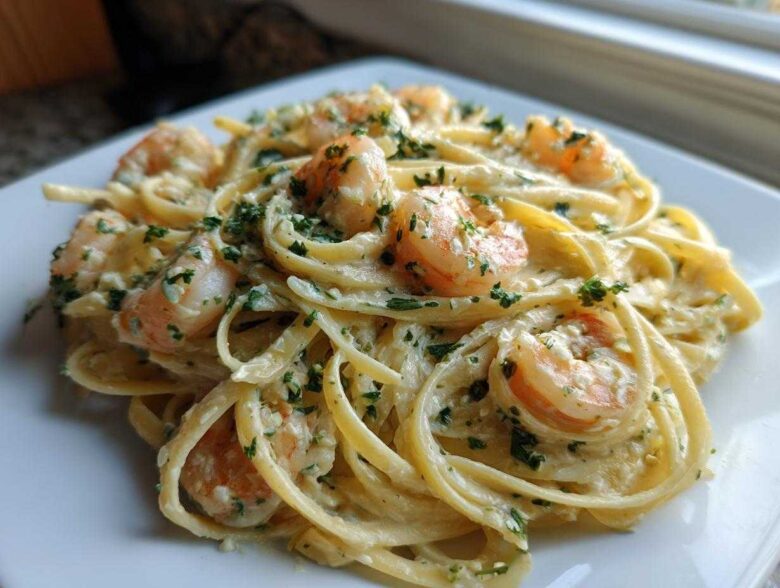 Close-up of a serving of Creamy Lemon Shrimp Pasta with Garlic Sauce, featuring fettuccine noodles and pink shrimp topped with parsley.
