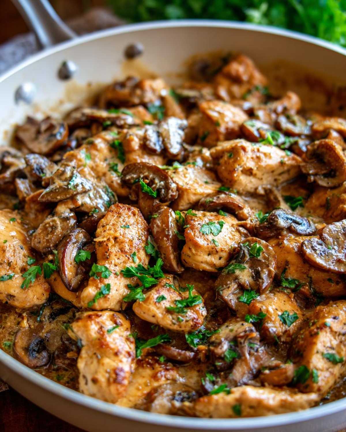 Close-up of seared chicken pieces and sliced mushrooms coated in a rich sauce in the Creamy Mushroom Alfredo Chicken Skillet.