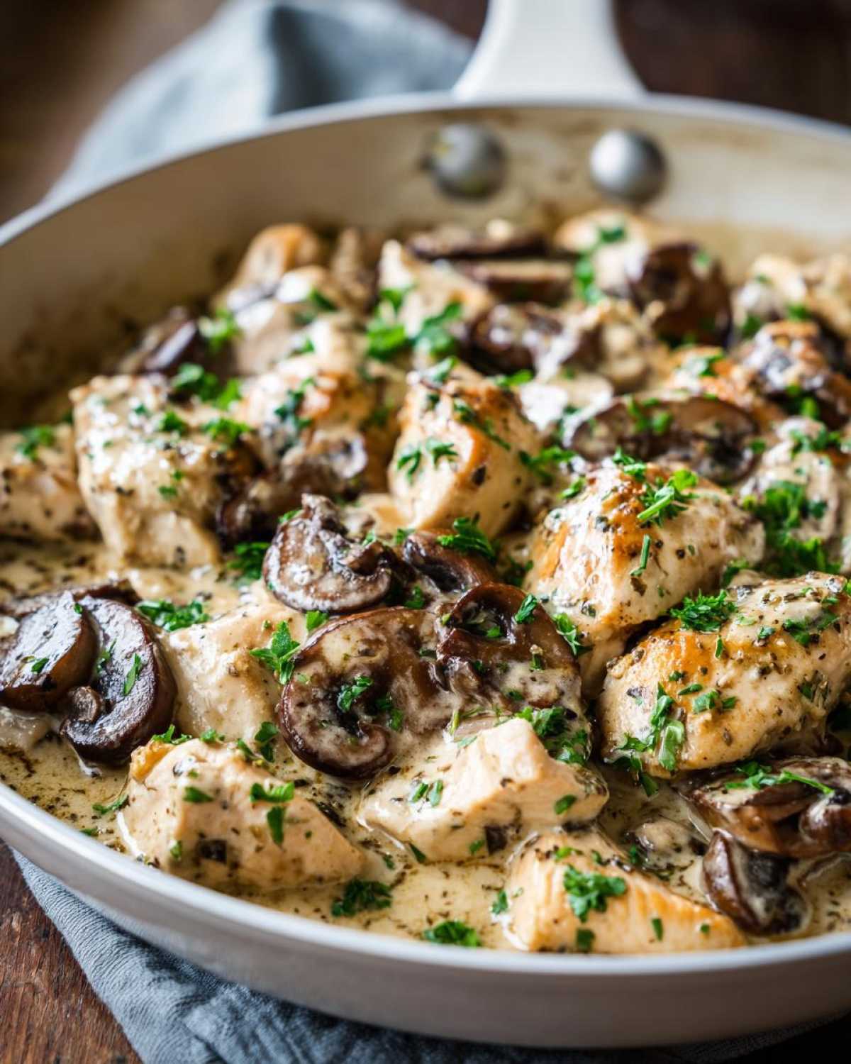 Close-up of pieces of chicken and sautéed mushrooms coated in a rich sauce in the Creamy Mushroom Alfredo Chicken Skillet.