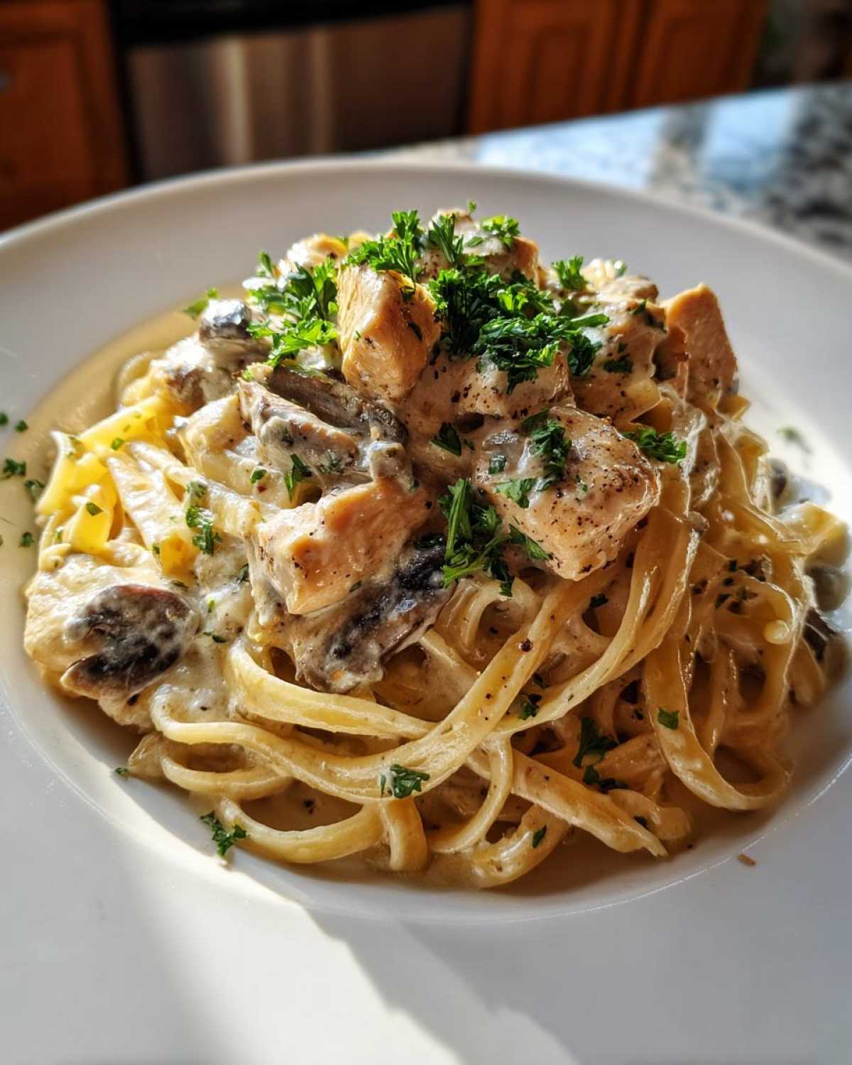 A close-up of a serving of Creamy Mushroom Chicken Alfredo Pasta garnished with fresh parsley.