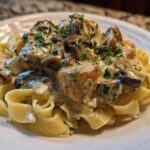 A close-up of Creamy Mushroom Chicken Pasta with Garlic Sauce served over egg noodles, garnished with parsley.