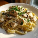 A close-up of creamy mushroom chicken pasta with parmesan cheese and fresh parsley garnish.