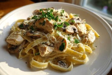 A close-up of creamy mushroom chicken pasta with parmesan cheese and fresh parsley garnish.