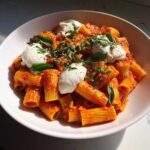 A bowl of Creamy Tomato Pasta with Burrata Cheese, topped with fresh basil and cracked pepper.
