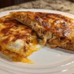 A perfectly crispy Cheesy Chicken Quesadilla cut in half showing melted cheese and shredded chicken filling.
