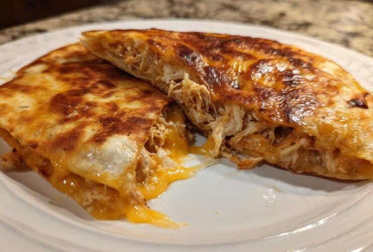 A perfectly crispy Cheesy Chicken Quesadilla cut in half showing melted cheese and shredded chicken filling.