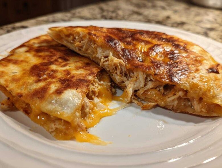 A perfectly crispy Cheesy Chicken Quesadilla cut in half showing melted cheese and shredded chicken filling.