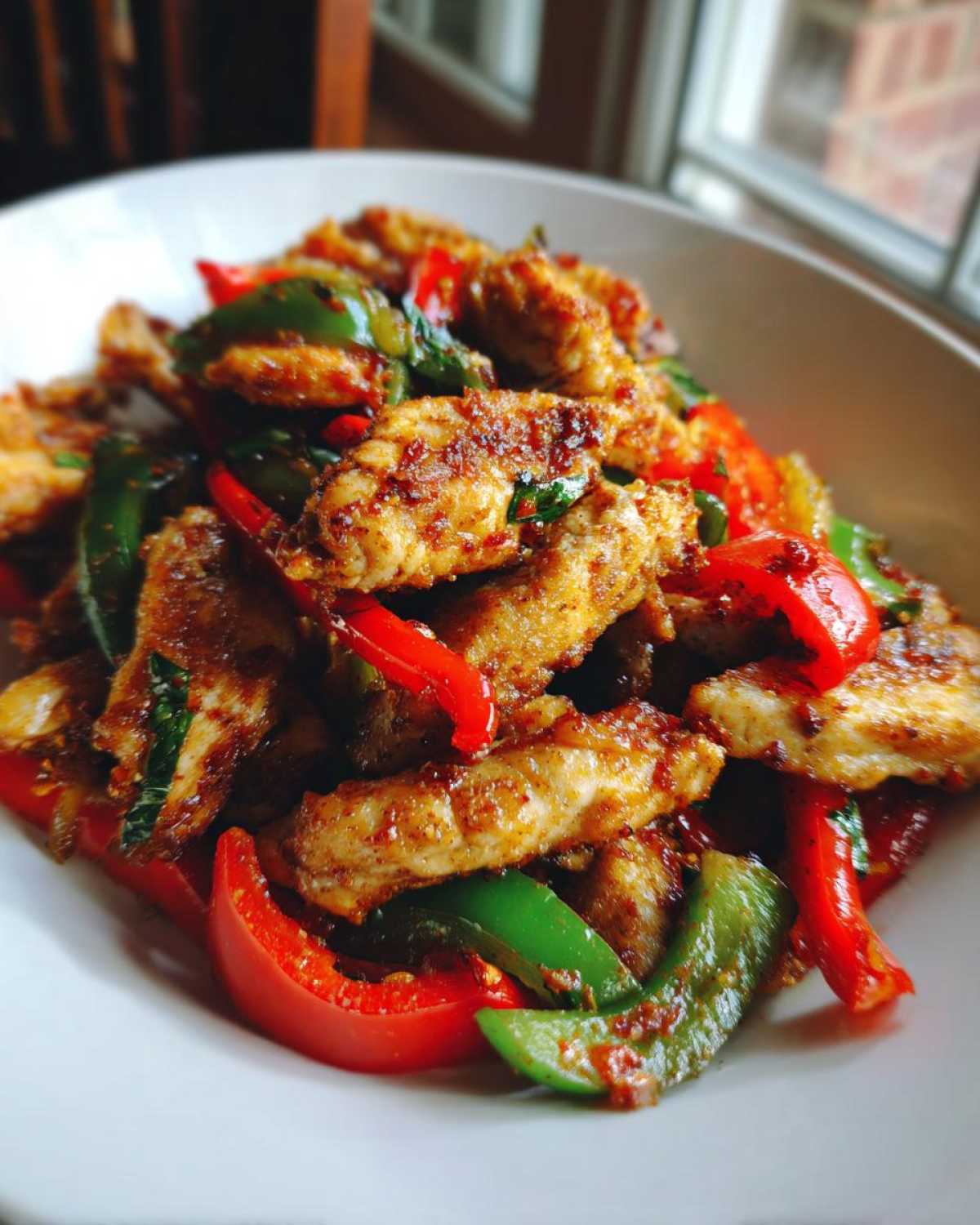 Close-up of crispy chicken fajitas mixed with vibrant red and green sautéed peppers.