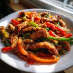 Close-up of Crispy Chicken Fajitas featuring breaded chicken strips mixed with vibrant sautéed red, green, and orange bell peppers.