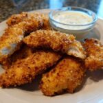 Golden brown Crispy Chicken Tenders with Garlic Parmesan Dip served on a white plate.