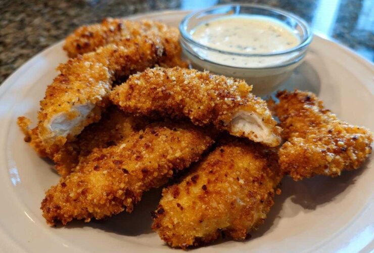 Golden brown Crispy Chicken Tenders with Garlic Parmesan Dip served on a white plate.