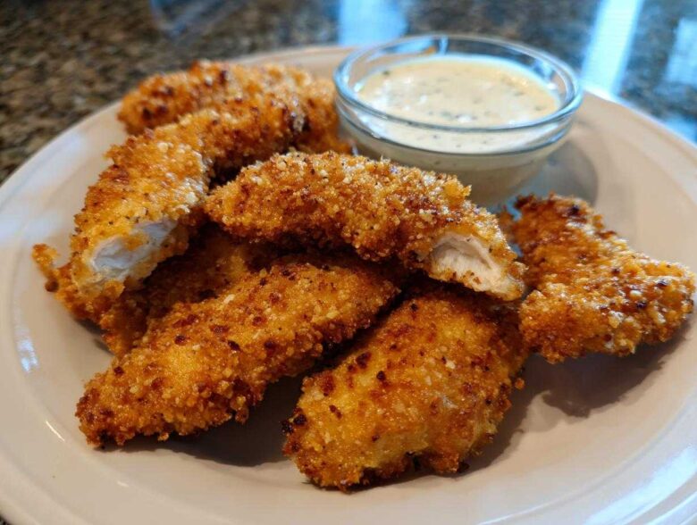 Golden brown Crispy Chicken Tenders with Garlic Parmesan Dip served on a white plate.