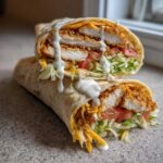 A cross-section view of a Crispy Chicken Wrap with Creamy Ranch Sauce, showing crispy chicken, lettuce, tomato, and cheese.