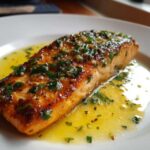 A close-up of a perfectly cooked Garlic Butter Salmon with crispy edges resting in melted butter sauce.