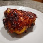 Close-up of a perfectly cooked Honey Garlic Chicken Thighs with incredibly crispy, dark, and glossy skin.