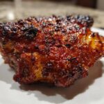 Close-up of a perfectly cooked Honey Garlic Chicken Thighs with dark, glossy, and crispy skin.