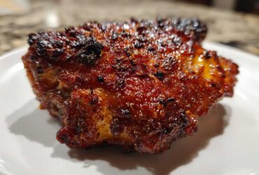 Close-up of a perfectly cooked Honey Garlic Chicken Thighs with dark, glossy, and crispy skin.