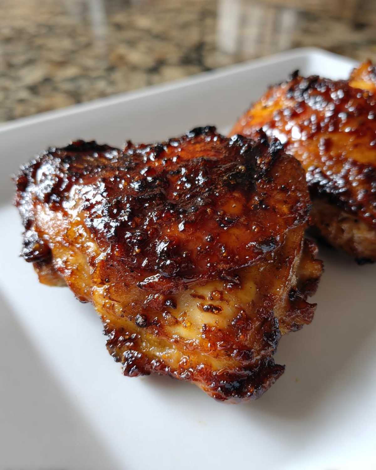 Close-up of perfectly cooked Honey Garlic Chicken Thighs with intensely caramelized, crispy skin.