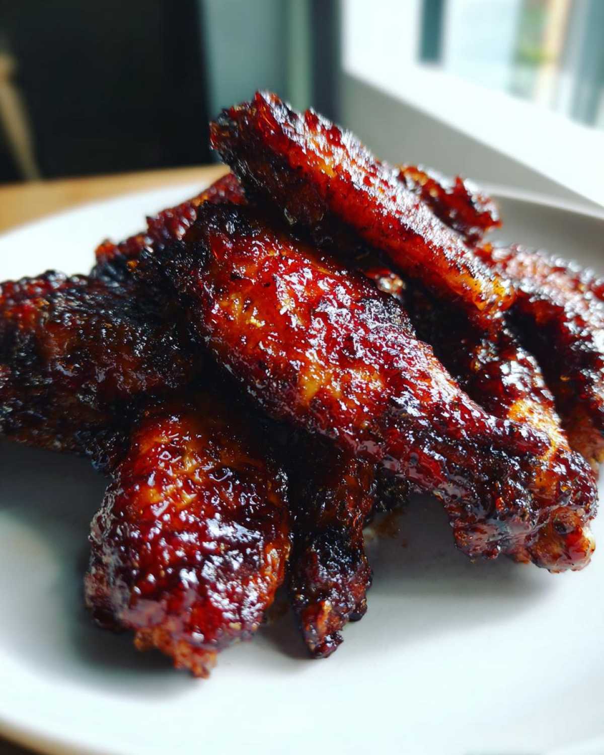 Close-up of perfectly cooked, crispy Sticky BBQ Chicken Wings Oven Style with a dark, glossy glaze.