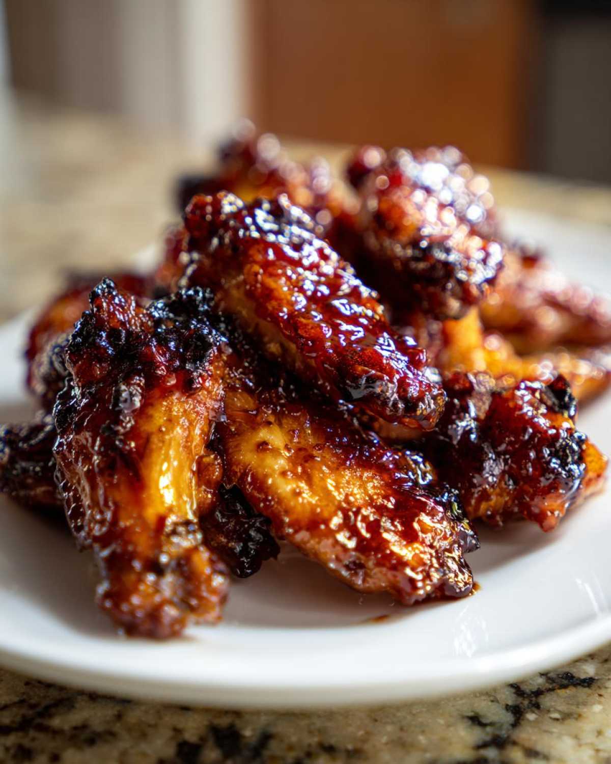 A close-up of oven-baked Sticky Teriyaki Chicken Wings coated in a thick, glossy, dark glaze.