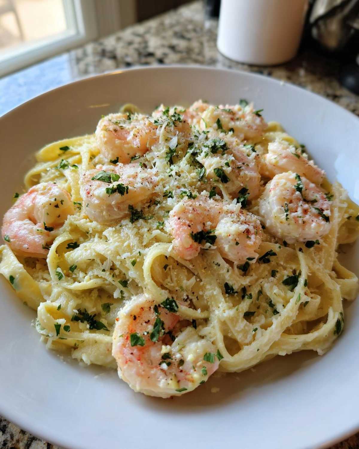 A close-up of creamy Garlic Butter Shrimp Alfredo Pasta topped with grated Parmesan and parsley.