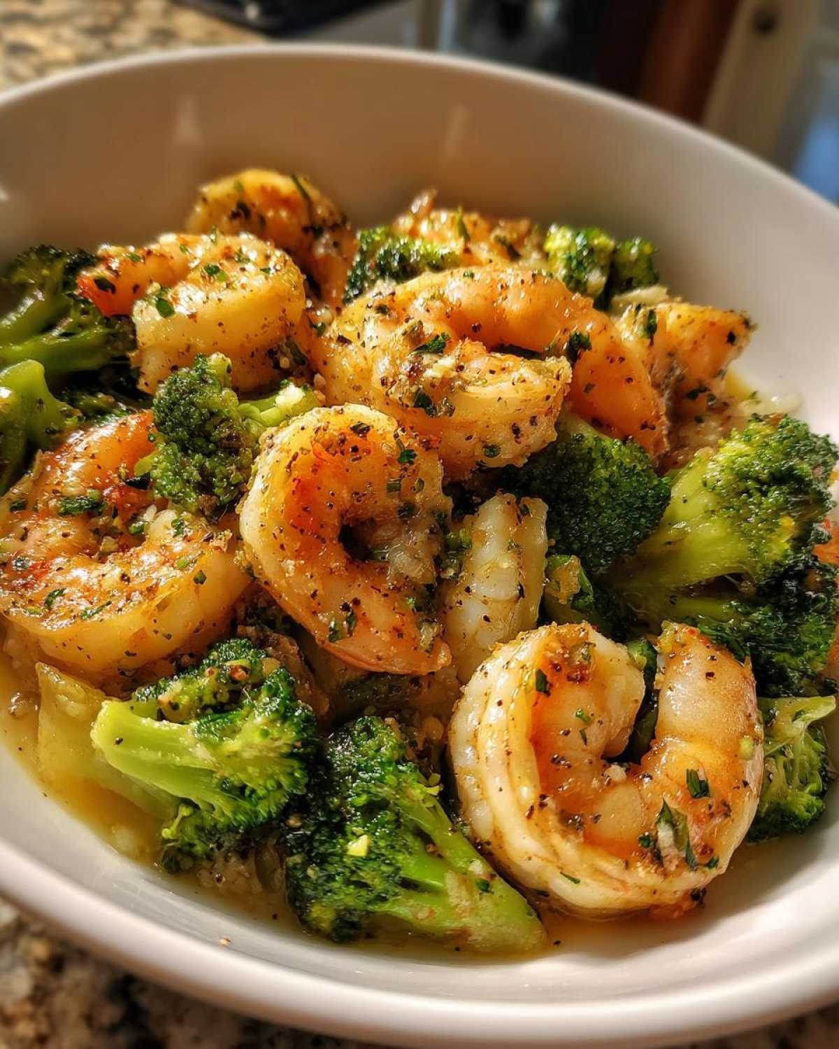 Close-up of succulent shrimp and bright green broccoli florets coated in garlic butter sauce.