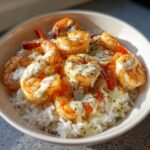 Close-up of a Garlic Butter Shrimp Rice Bowl topped with creamy garlic sauce and black pepper.