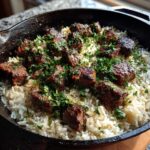 Close-up of Garlic Butter Steak and Rice Skillet Dinner topped with fresh parsley in a cast iron pan.