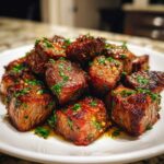 A mound of perfectly seared Garlic Butter Steak Bites with Juicy Center, glistening with butter sauce and topped with fresh parsley.