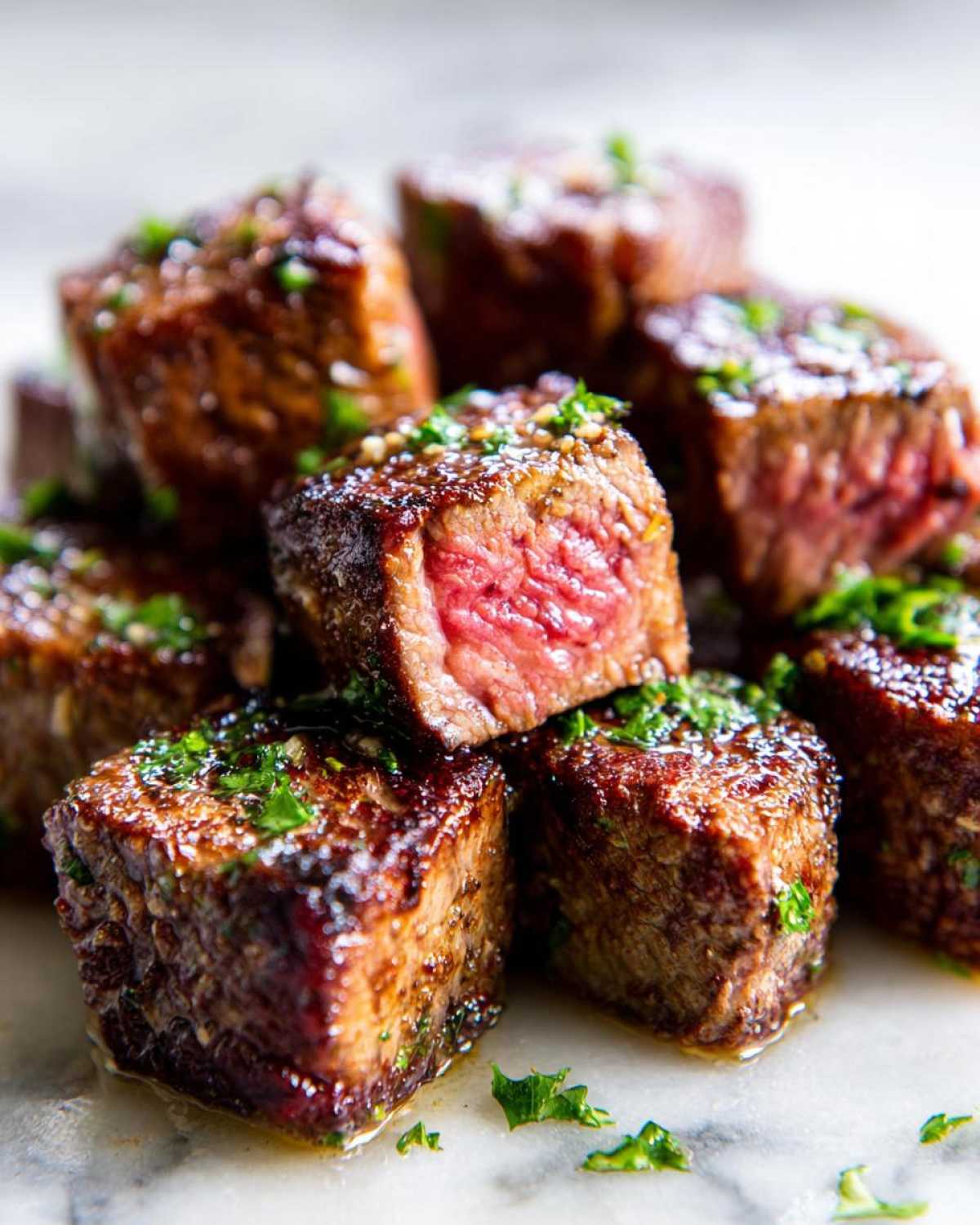 Close-up of perfectly seared Garlic Butter Steak Bites with a juicy, medium-rare center, garnished with parsley.
